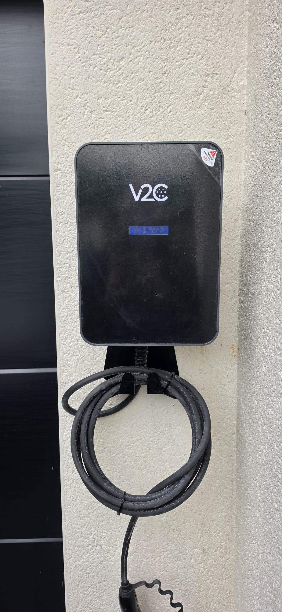 Borne de recharge V2C installée sur maison avec porte de garage