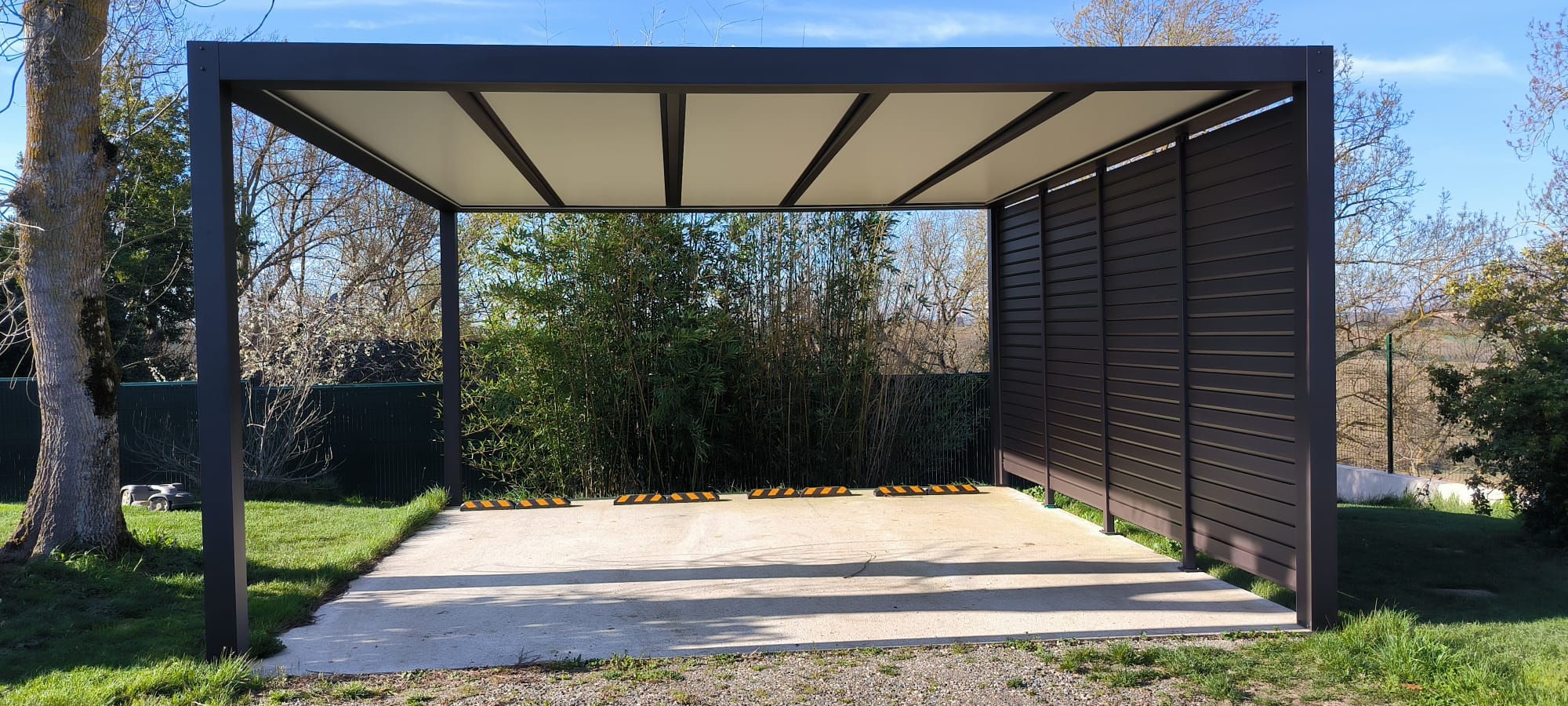 Pergola aluminium anthracite avec toit polycarbonate et claustra latéral — réalisation Bretagne