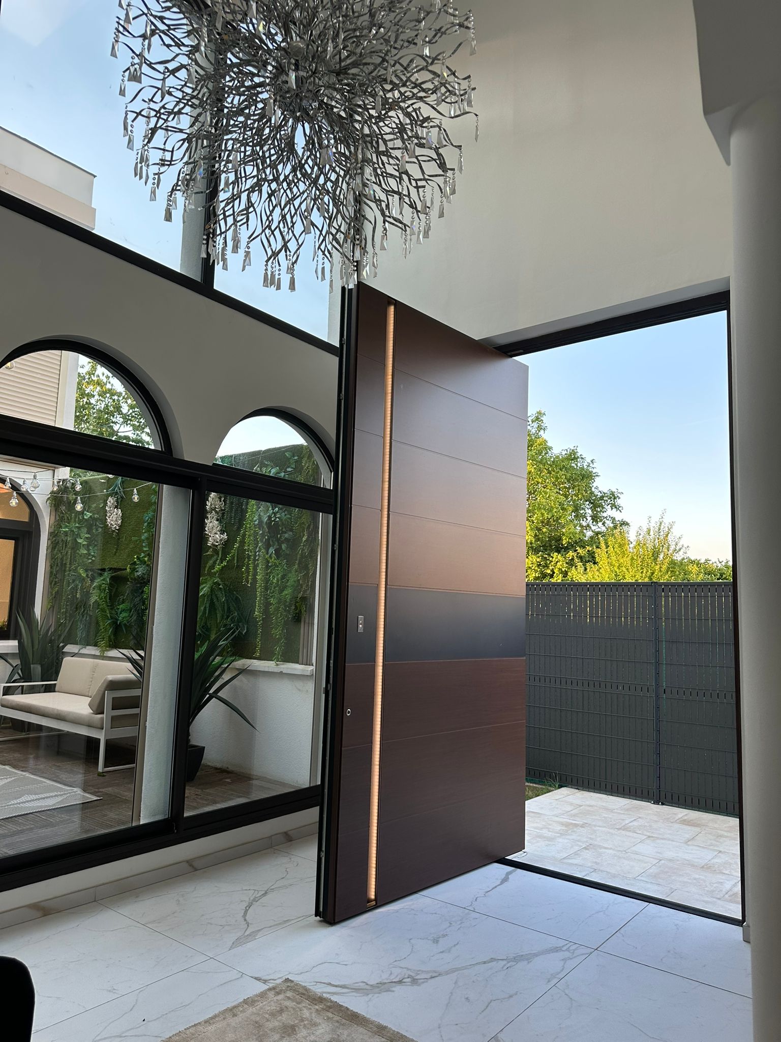 Porte à pivot Tehni grande largeur ouverte sur terrasse — réalisation Larmor-Plage, Morbihan